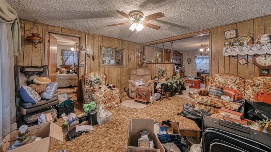 Misc room with carpet floors, wood walls, ceiling fan, and a textured ceiling