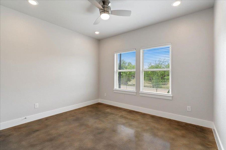 This front bedroom includes a ceiling fan, recessed lighting, and a front yard view. This front bedroom includes a ceiling fan, recessed lighting, and a front yard view.