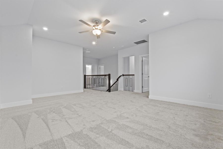 Carpeted empty room featuring vaulted ceiling and ceiling fan