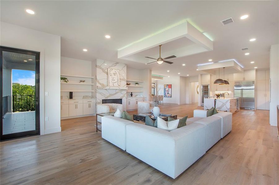 Living room with light hardwood / wood-style floors, sink, a high end fireplace, and ceiling fan