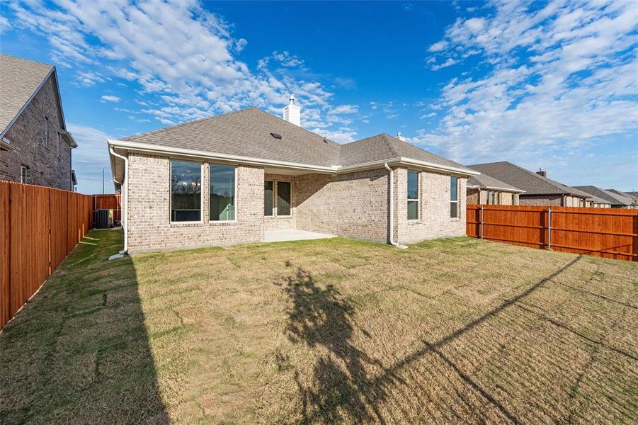 Back of property featuring a patio, roof with shingles, a fenced backyard, brick siding, and a chimney