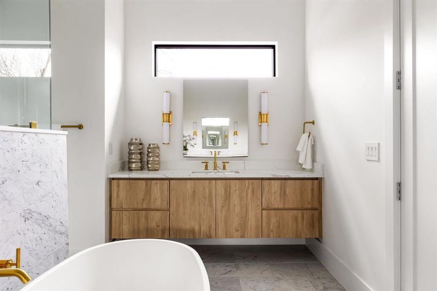 Bathroom with a freestanding bath, vanity, and baseboards