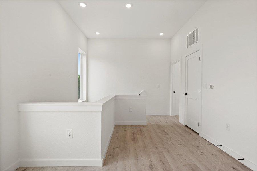 This bright space features light-colored flooring, recessed lighting, and a white interior door with black hardware