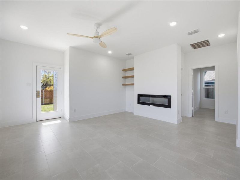 Unfurnished living room featuring a glass covered fireplace, recessed lighting, and a ceiling fan