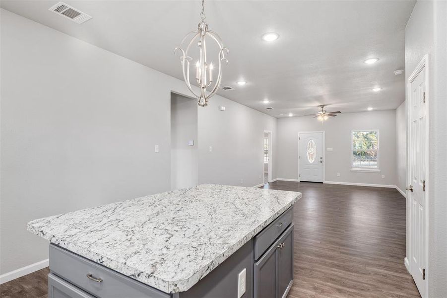 Kitchen with ceiling fan with notable chandelier, decorative light fixtures, gray cabinets, and a kitchen island