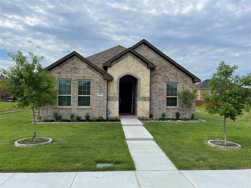 French country home with brick siding, a front lawn, and stone siding French country home with brick siding, a front lawn, and stone siding