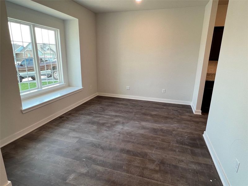 Spare room featuring baseboards and dark wood-style floors Spare room featuring baseboards and dark wood-style floors