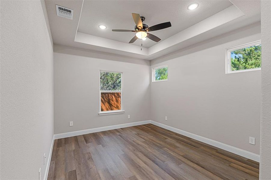 Unfurnished room with ceiling fan, wood-type flooring, and a tray ceiling