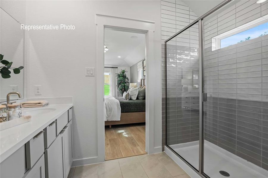 Bathroom featuring vanity, a wealth of natural light, a shower with shower door, and hardwood / wood-style floors