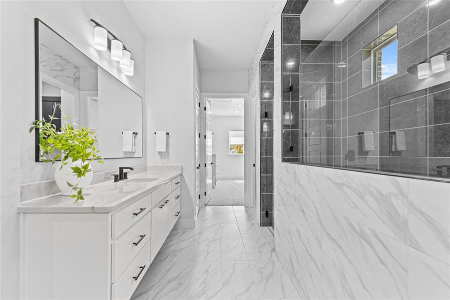 Bathroom featuring healthy amount of natural light, vanity, walk in shower, and light marble finish flooring
