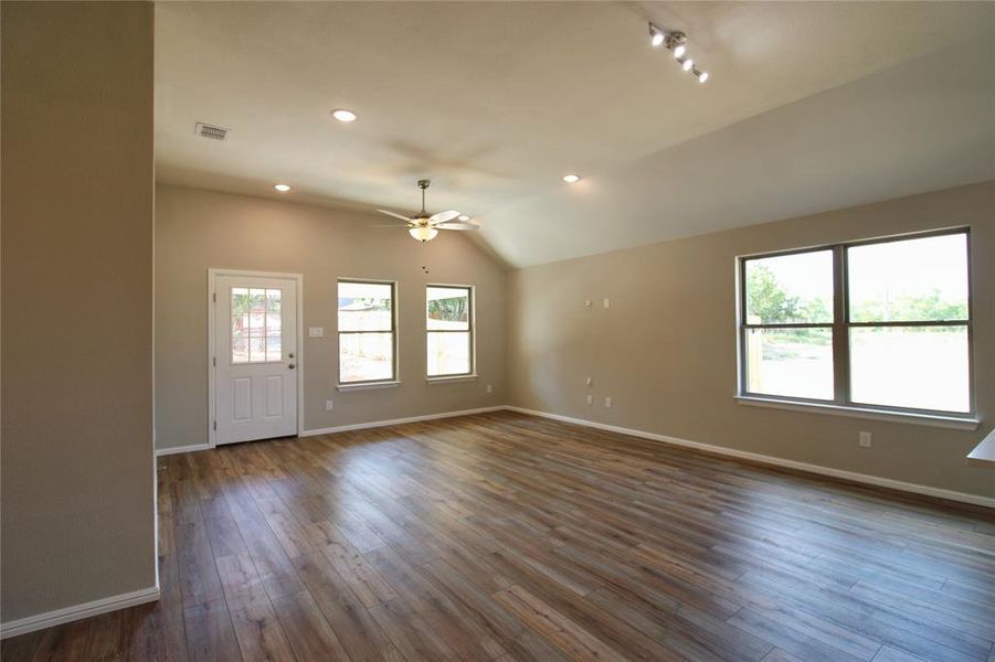 Empty room with lofted ceiling, recessed lighting, dark wood-style flooring, and ceiling fan