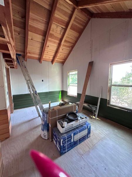 A room with wooden beam ceiling under construction with a clear view outside.