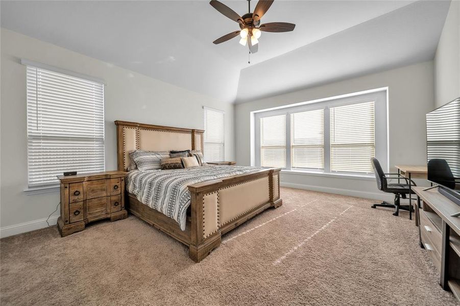 Bedroom with vaulted ceiling, an office area, a ceiling fan, and light carpet Bedroom with vaulted ceiling, an office area, a ceiling fan, and light carpet