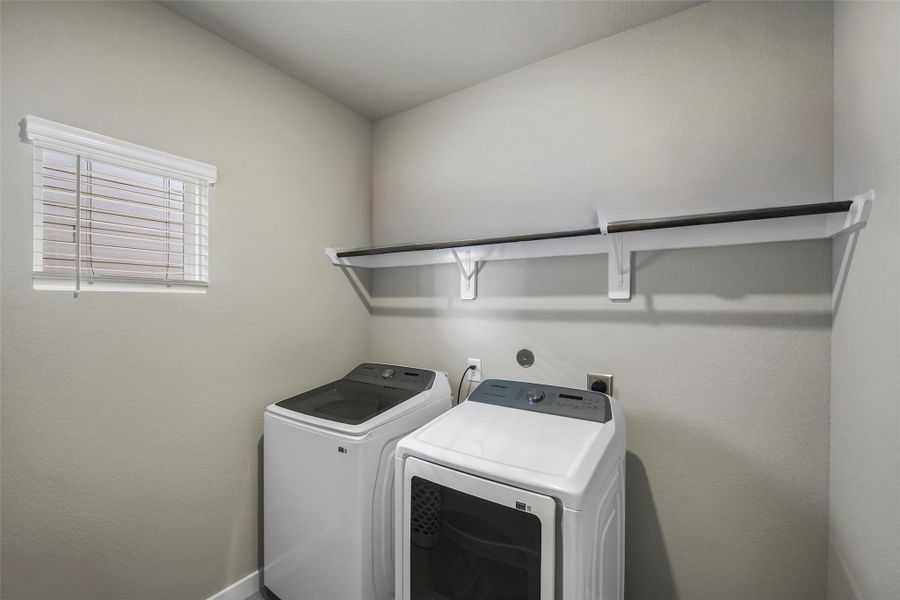 Bright and functional laundry room with ample storage with a wall-mounted shelf, and a window for natural light.