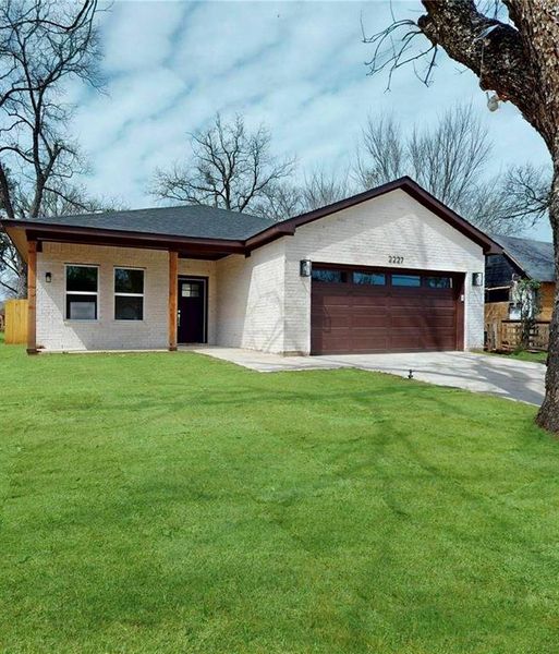 Single story home with an attached garage, concrete driveway, a front lawn, and brick siding