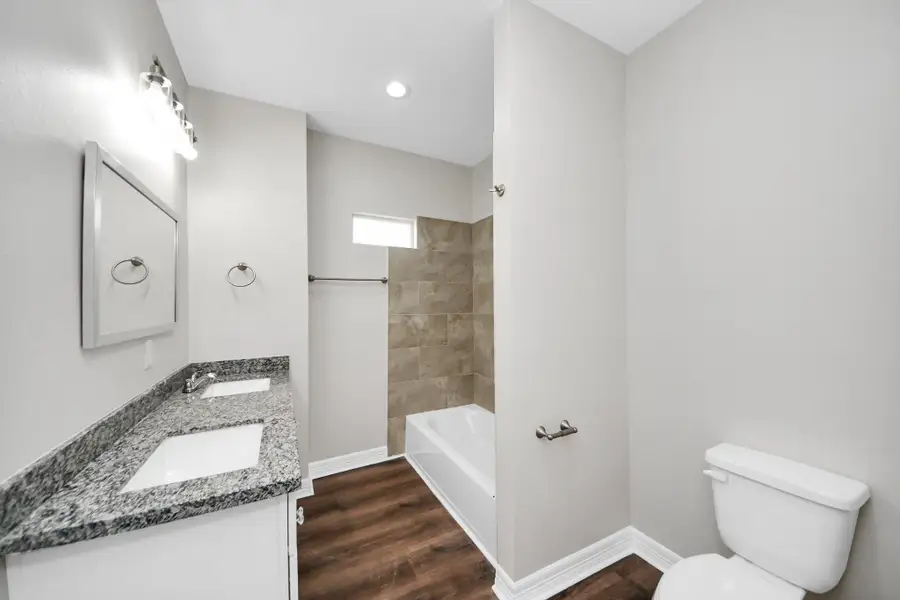 This secondary hall bathroom is both stylish and functional, featuring durable LVP flooring, granite countertops with dual sinks, and plenty of storage space—perfect for family use and guests alike - (representation photo).