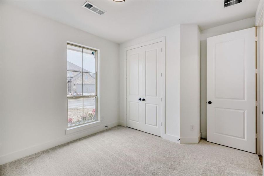 Unfurnished bedroom with light colored carpet and a closet