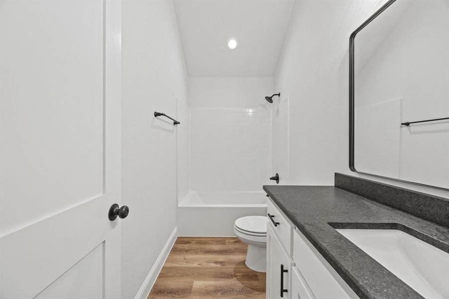 Bathroom featuring vanity,  shower combination, and light wood finished floors