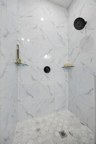 Enjoy the walk in shower with sleek tile and glass shelves.