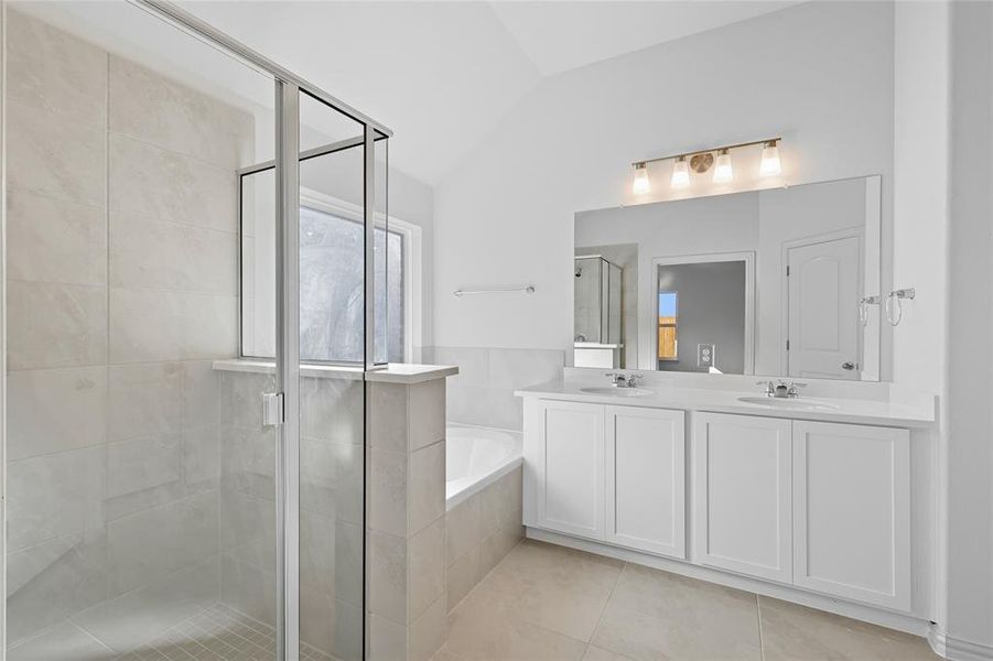 Bathroom featuring a shower stall, a bath, double vanity, lofted ceiling, and light tile patterned floors Bathroom featuring a shower stall, a bath, double vanity, lofted ceiling, and light tile patterned floors
