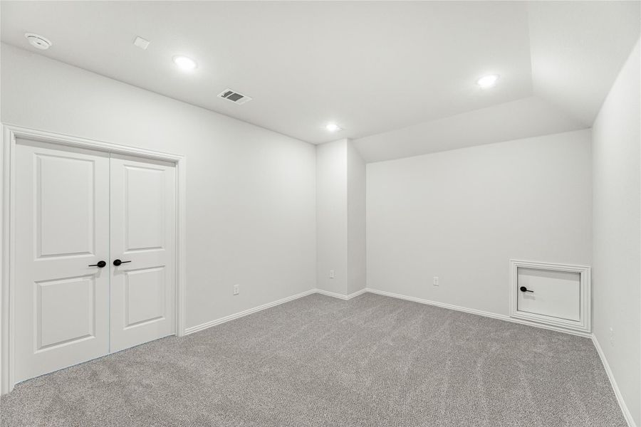 Empty bedroom with gray carpet, double doors, recessed lighting, and small wall access panel
