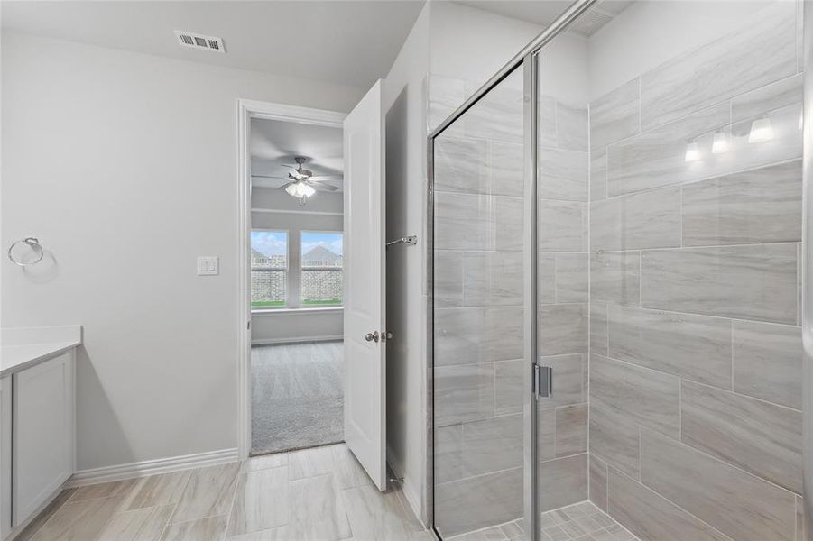 Bathroom featuring ceiling fan, a shower stall, and vanity