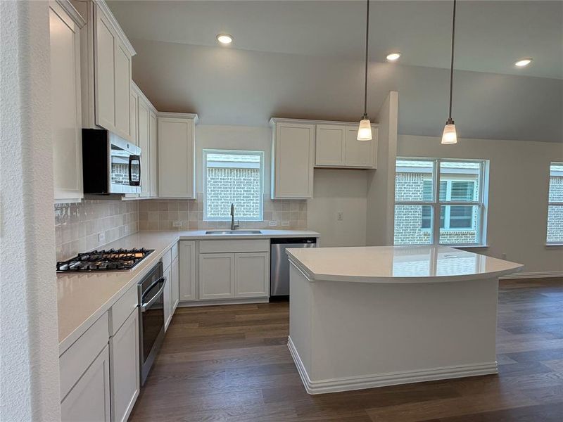 Modern kitchen featuring white cabinetry, light countertops, wood-finish flooring, stainless steel appliances, and recessed lighting