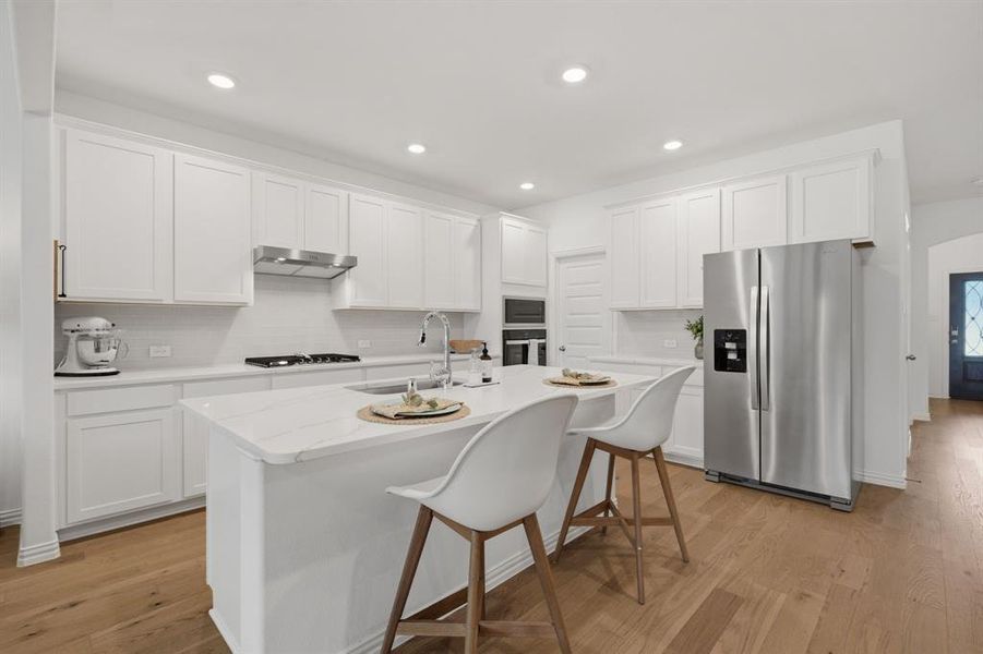 Bright white chef’s kitchen with quartz countertops, gas cooktop, stainless appliances, and a large island perfect for everyday living and entertaining.