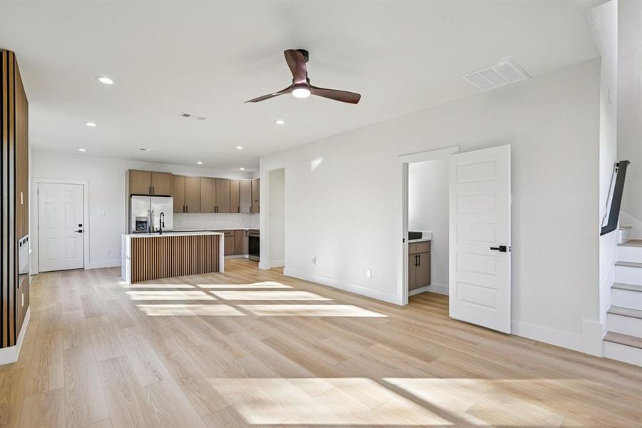 Unfurnished living room featuring a ceiling fan, recessed lighting, light wood-type flooring, and stairway