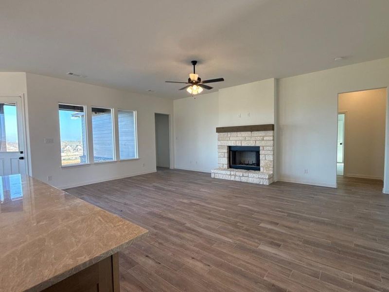Unfurnished living room with a fireplace, dark wood-style flooring, and a ceiling fan