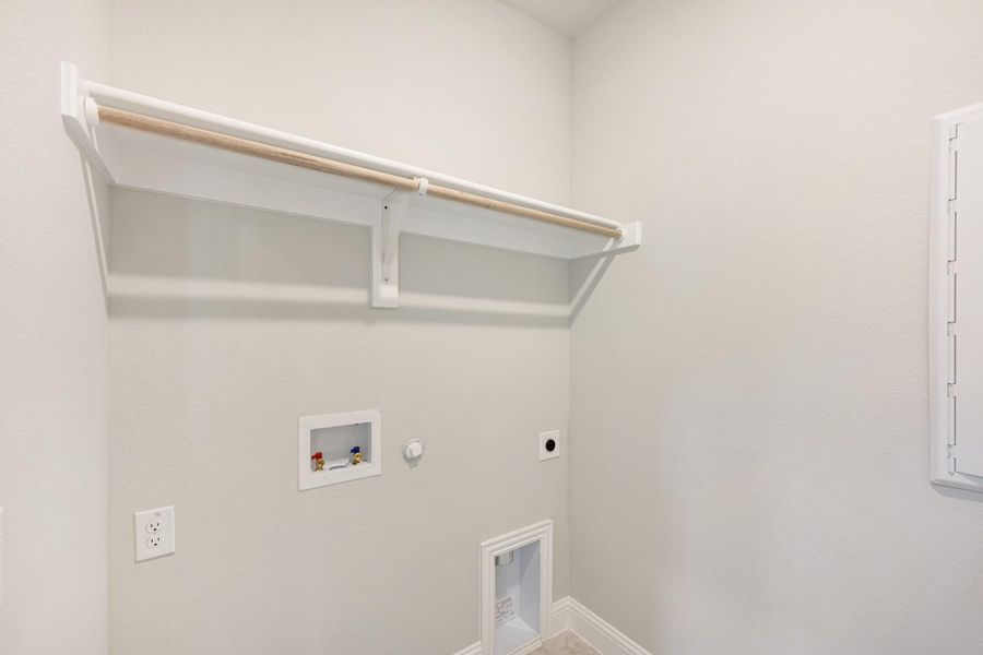 Laundry room with wall-mounted shelf, hanging rod, washer hookups, and dryer vent connection