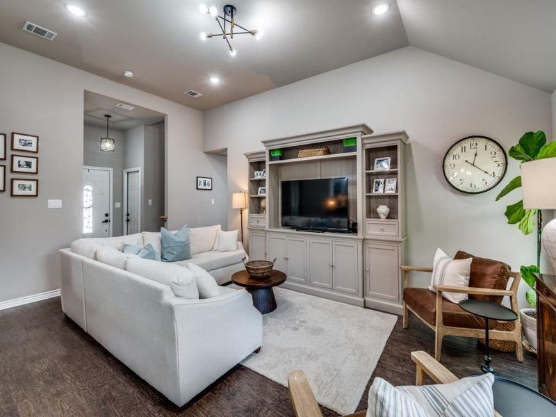 Living room featuring dark wood-style flooring, baseboards, lofted ceiling, and recessed lighting Living room featuring dark wood-style flooring, baseboards, lofted ceiling, and recessed lighting