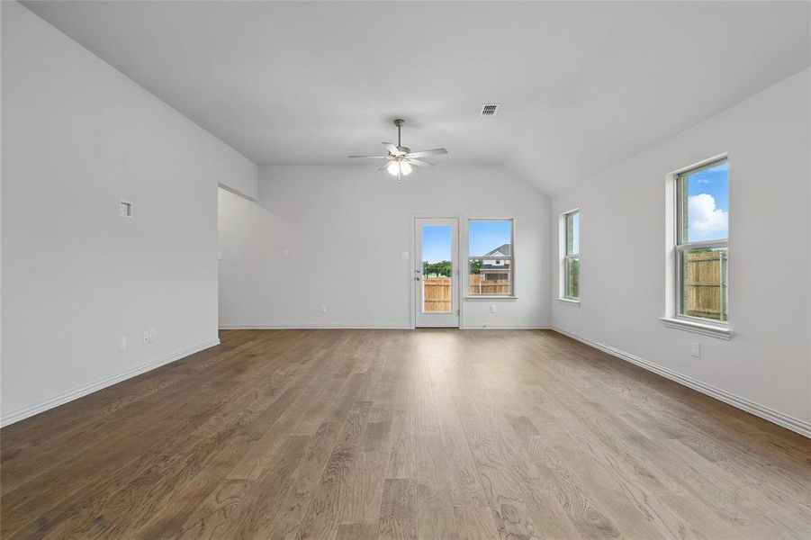 Spare room with light wood finished floors, vaulted ceiling, and a ceiling fan