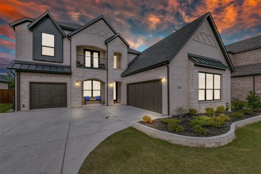 French country home with a garage, a balcony, and a yard