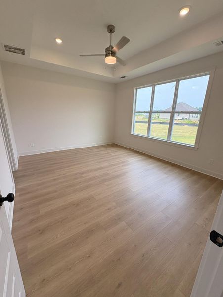 Spacious room featuring wood-finish flooring, a contemporary ceiling fan, and recessed lighting