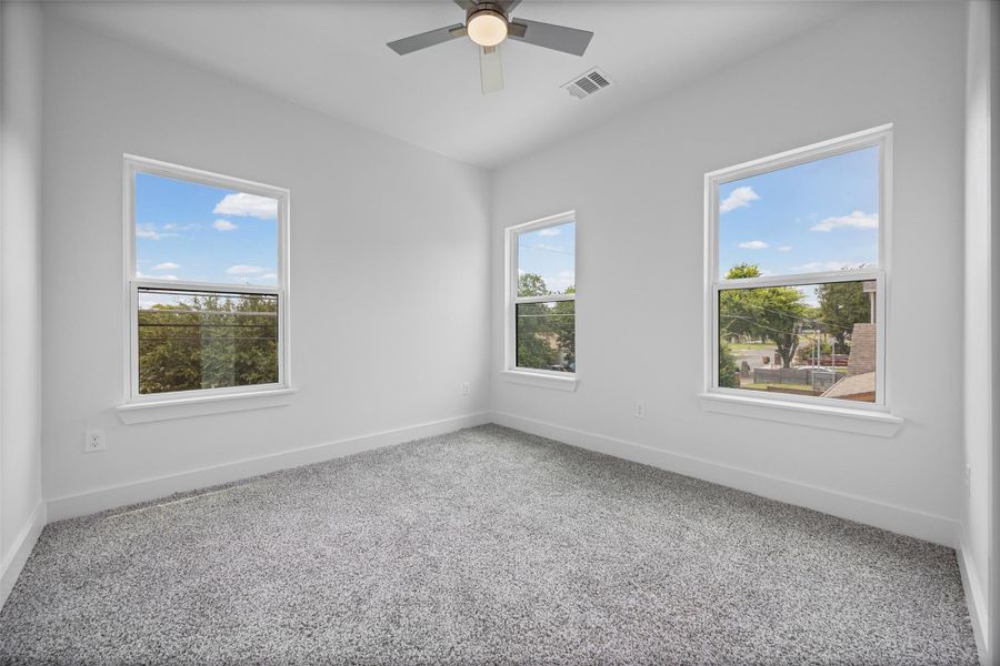 Three generous windows and plush carpet define this serene, naturally illuminated bedroom. Three generous windows and plush carpet define this serene, naturally illuminated bedroom.