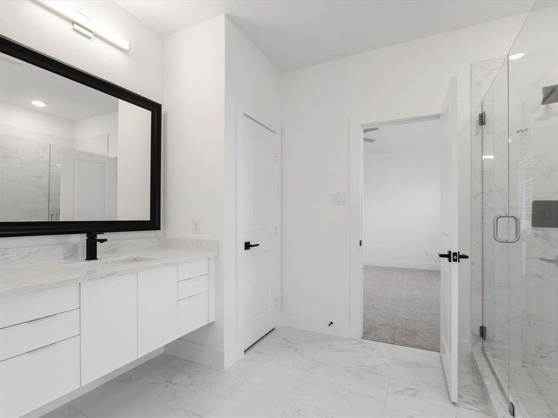 Primary Bathroom featuring vanity, a marble finish shower, and light marble finish floors