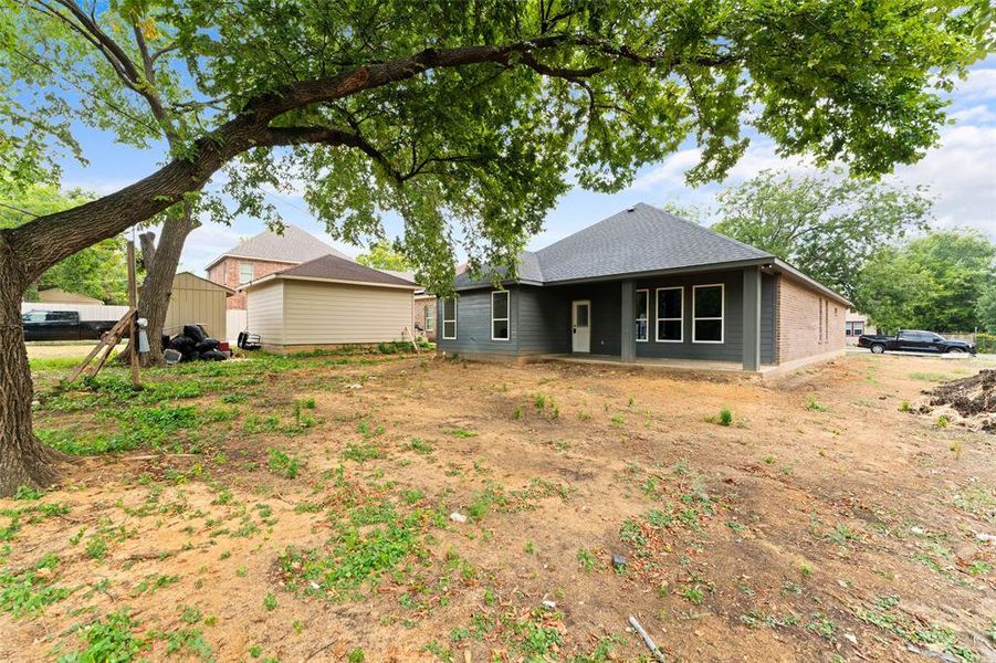 Rear view of house with a patio area and a shingled roof