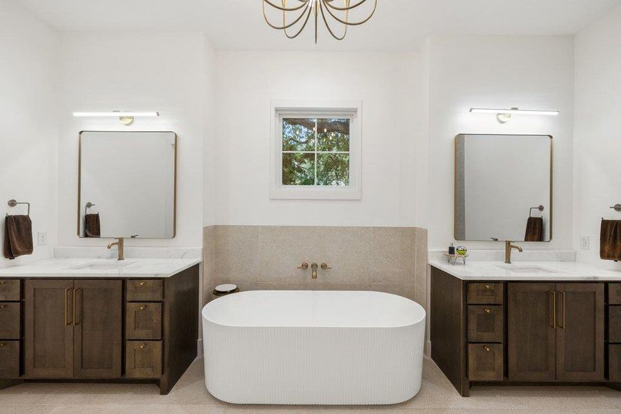Luxurious primary bath with dual vanities, soaking tub, and elegant gold fixtures. Luxurious primary bath with dual vanities, soaking tub, and elegant gold fixtures.