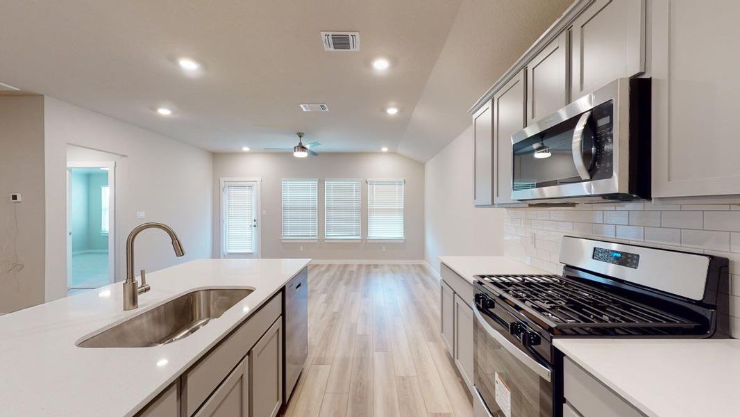 Kitchen with stainless steel appliances, light wood finished floors, gray cabinetry, recessed lighting, and tasteful backsplash