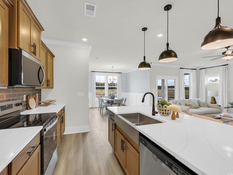 Kitchen with stainless steel appliances, decorative light fixtures, light stone countertops, light wood finished floors, and brown cabinets Kitchen with stainless steel appliances, decorative light fixtures, light stone countertops, light wood finished floors, and brown cabinets