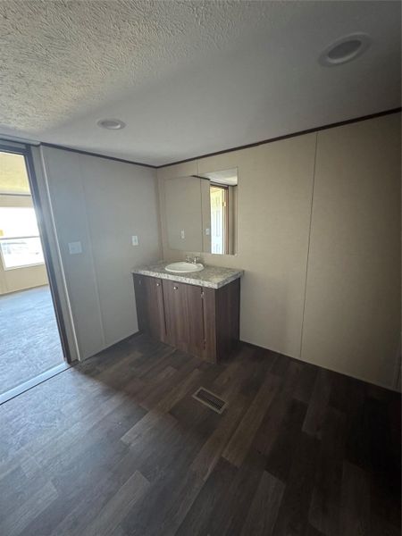Dark wood floors and a recessed light ceiling complement the modern vanity space.