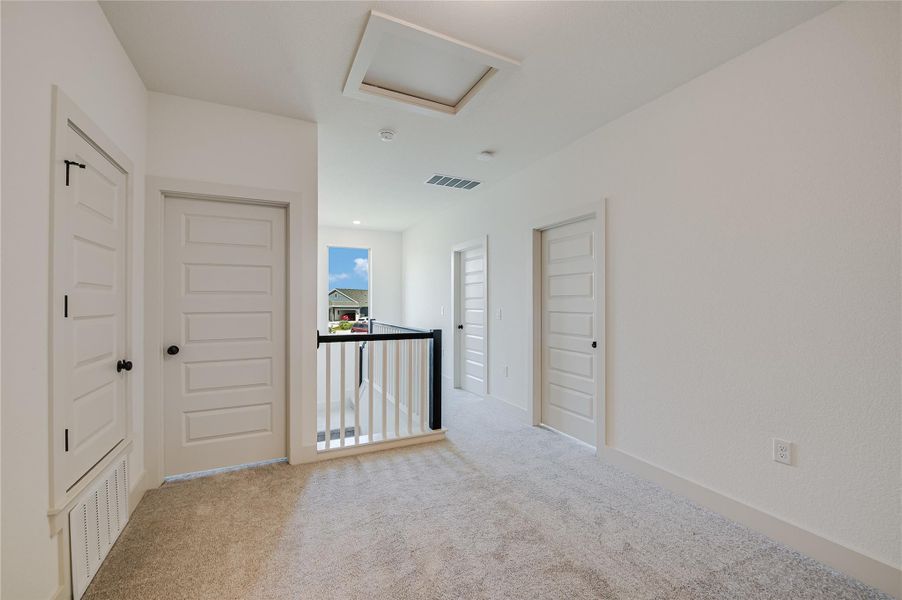 Hallway with attic access, light carpet, and an upstairs landing