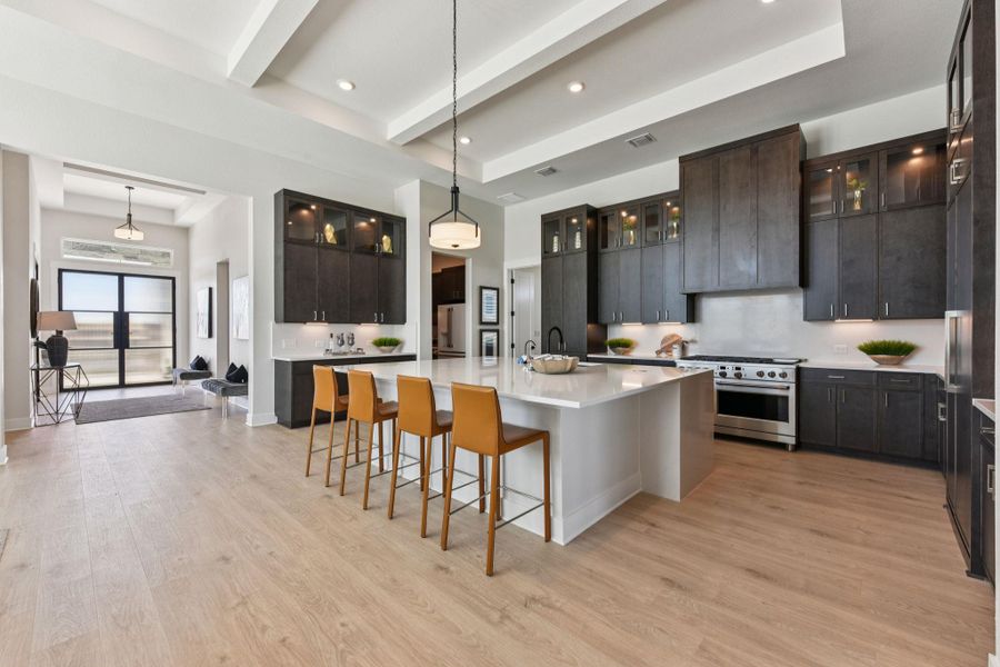 Kitchen with glass insert cabinets, a breakfast bar, decorative light fixtures, stainless steel appliances, and beamed ceiling