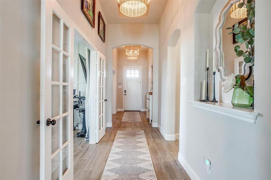 Hall featuring french doors, a chandelier, and light wood-type flooring