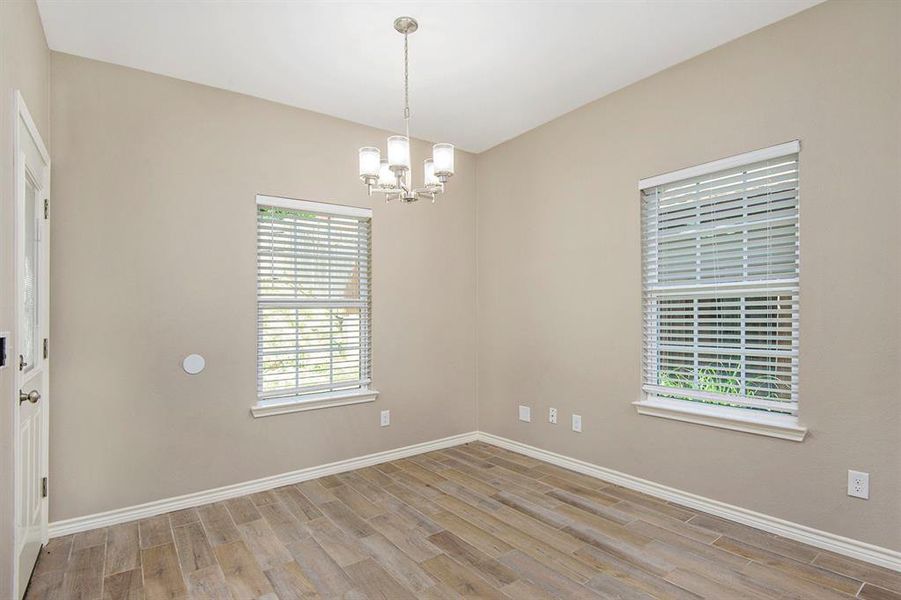 Spare room with wood finished floors and a chandelier