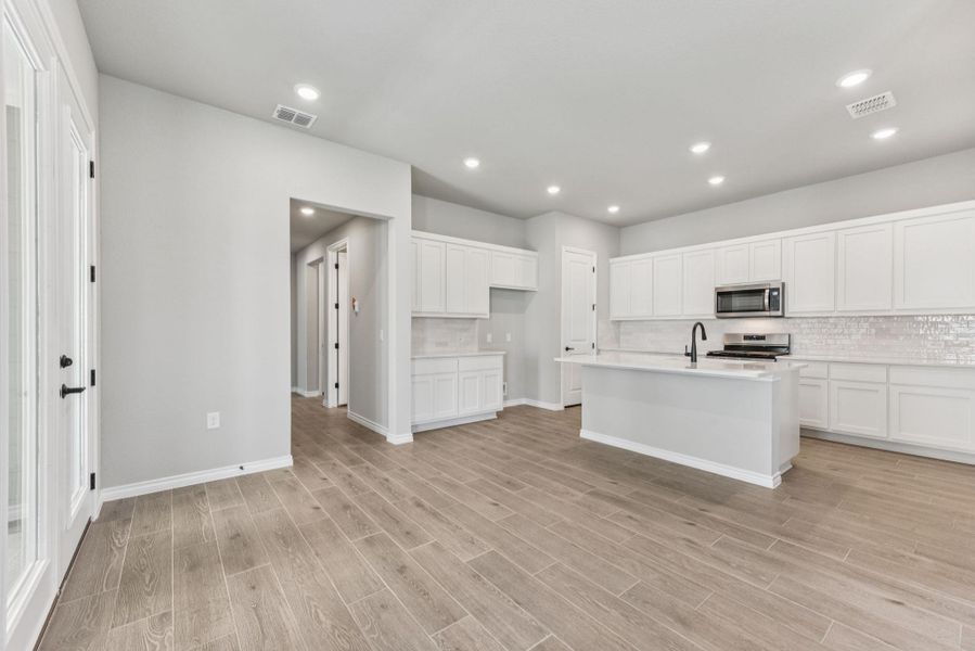 Kitchen featuring decorative backsplash, white cabinetry, a kitchen island with sink, recessed lighting, and appliances with stainless steel finishes