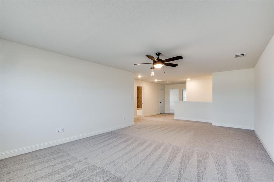 Unfurnished room featuring light carpet and a ceiling fan Unfurnished room featuring light carpet and a ceiling fan