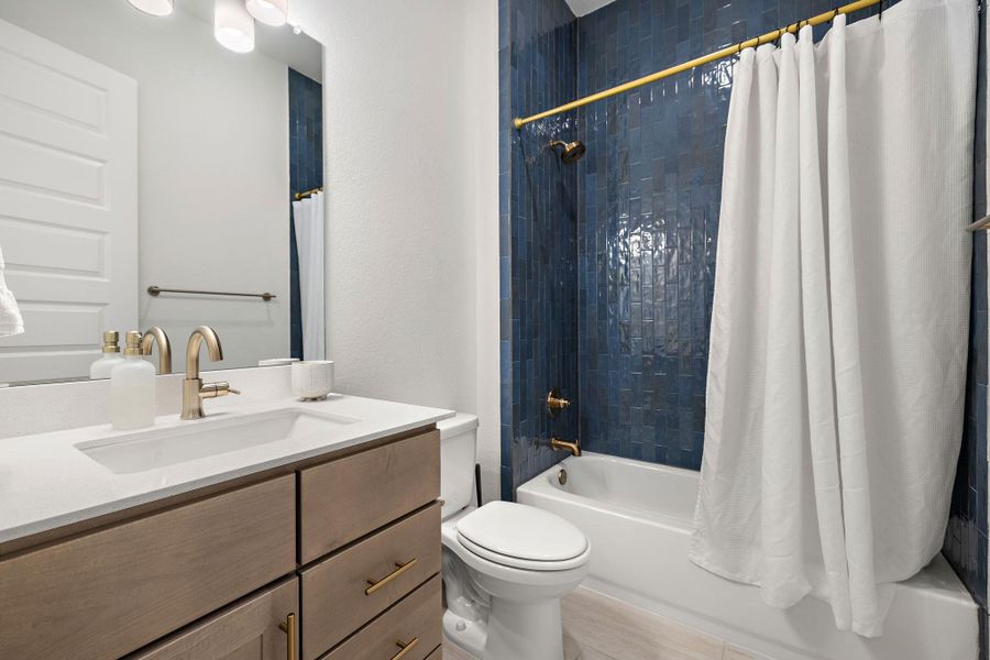 Bathroom featuring a blue subway tile shower surround, a built-in bathtub, and a single vanity with a white countertop