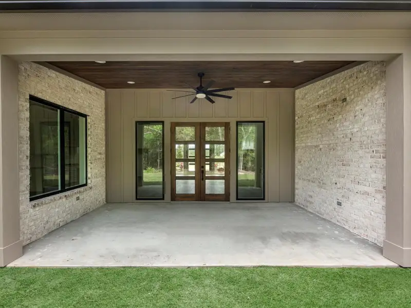 Private covered patio with wood-paneled ceiling and serene wooded views.